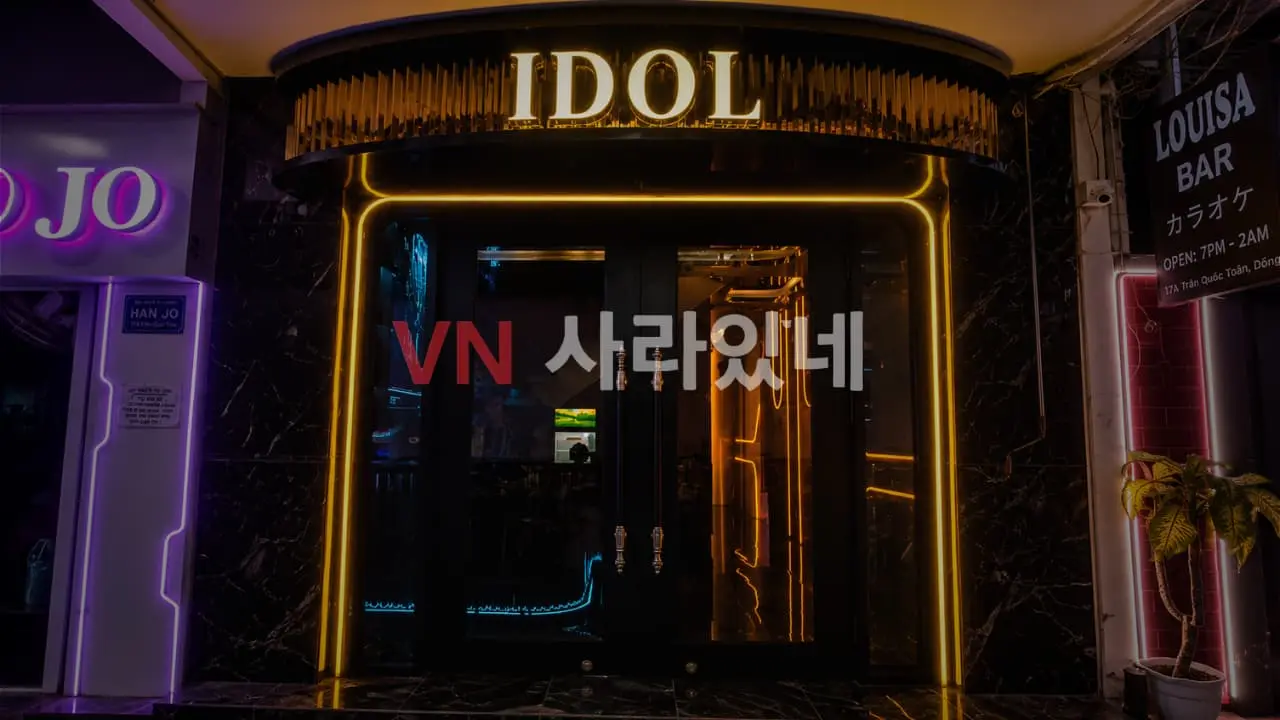 호치민 아이돌 바 건물 입구 전경 — 황금 빛 IDOL 간판과 네온 프레임 정문 야경